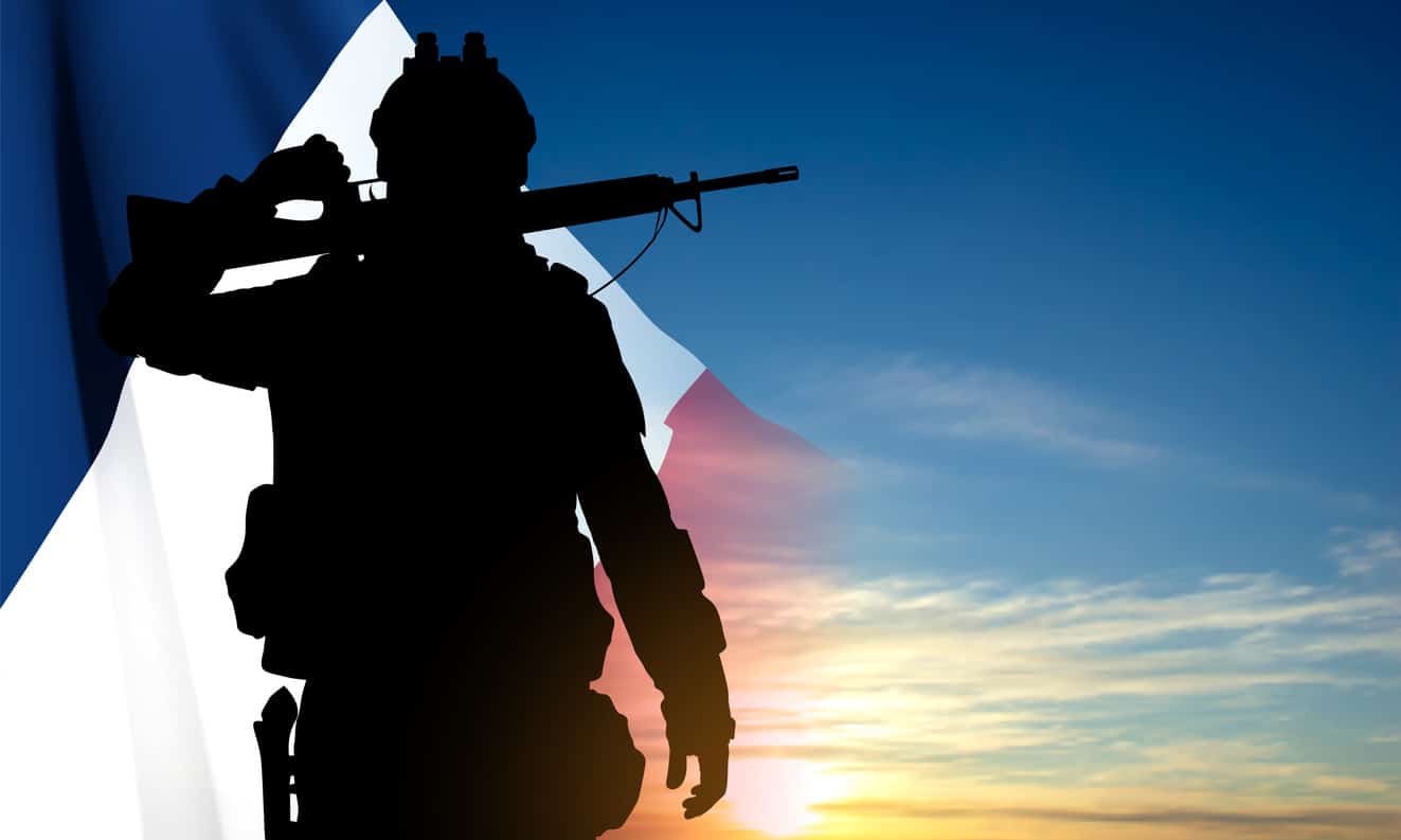 Silhouette of French soldier on background of sky and French flag